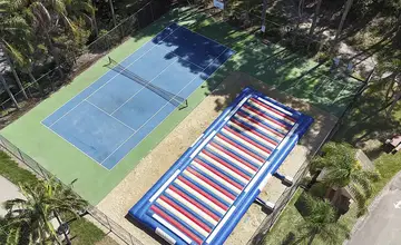 Aerial view of the jumping pillow and tennis and pickleball courts at Wairo Beach Holiday Park.